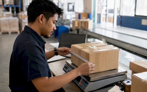 Hands weighing and inspecting shipping parcel in warehouse