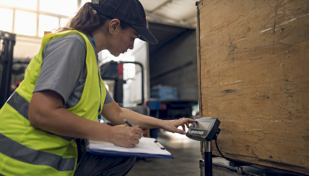 Worker measuring shipment box in warehouse
