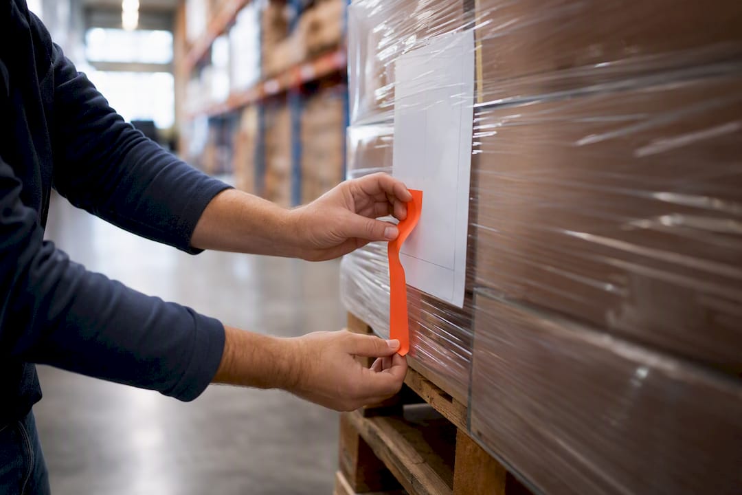 Hands tagging limited access shipment in warehouse