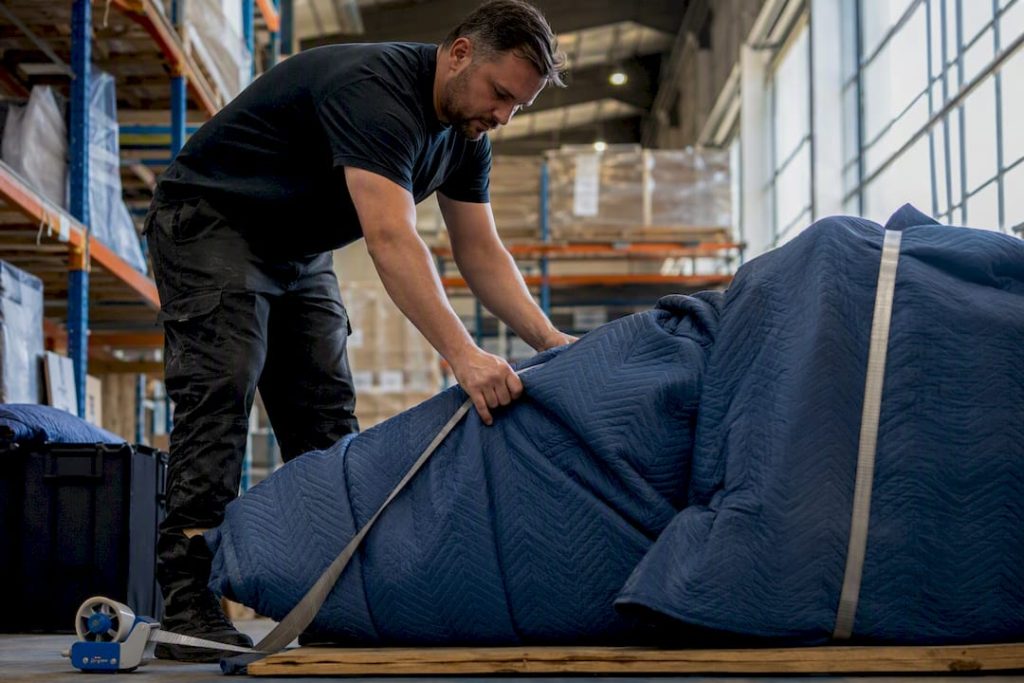Worker wrapping fragile freight in padded blankets