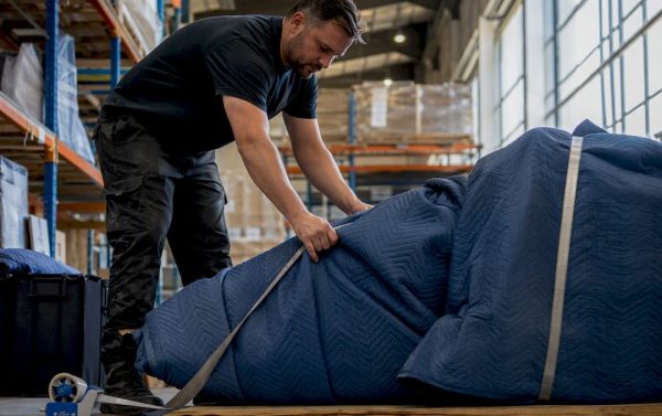 Worker wrapping fragile freight in padded blankets