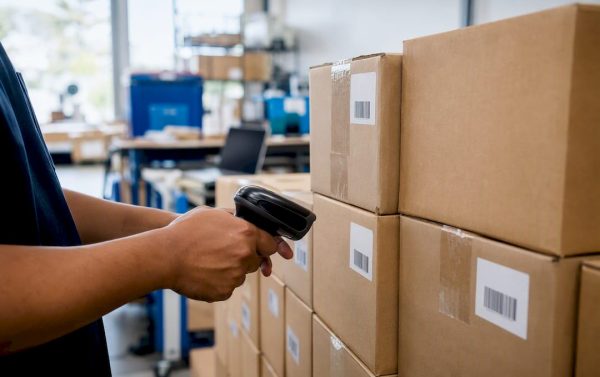 Hands scanning barcoded boxes in warehouse