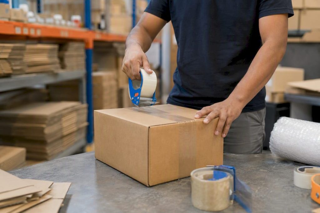 Hands packing ecommerce shipment box in warehouse