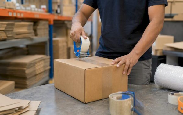 Hands packing ecommerce shipment box in warehouse
