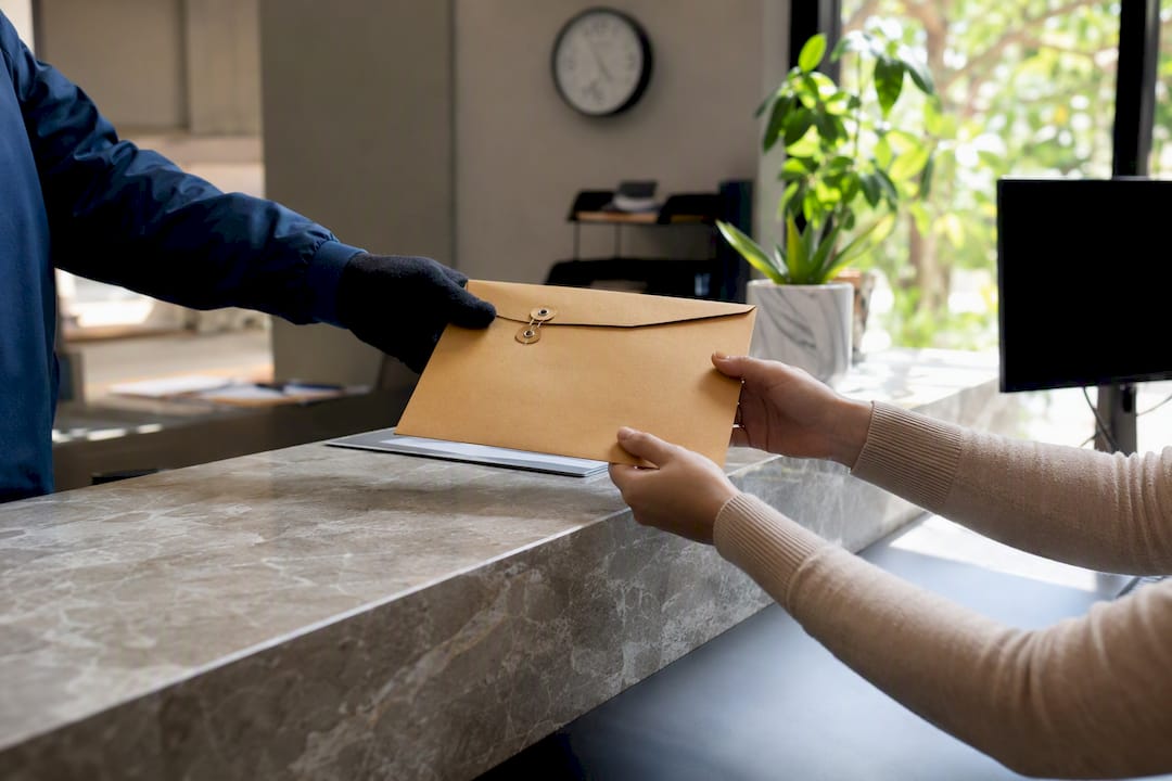 Courier handing certificate envelope at chamber office