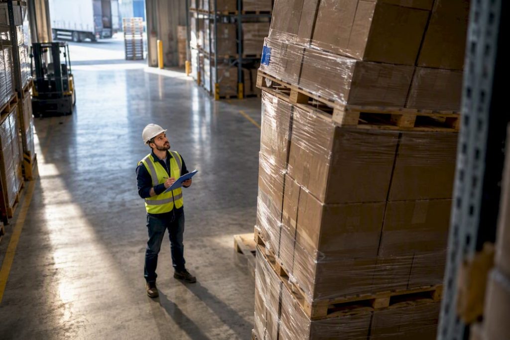 Warehouse worker inspecting stacked pallets