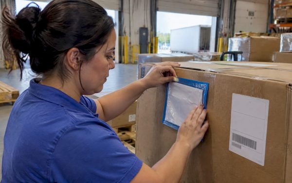 Clerk attaching packing list pouch to carton
