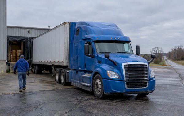 Blue tractor-trailer waiting at a rural freight yard
